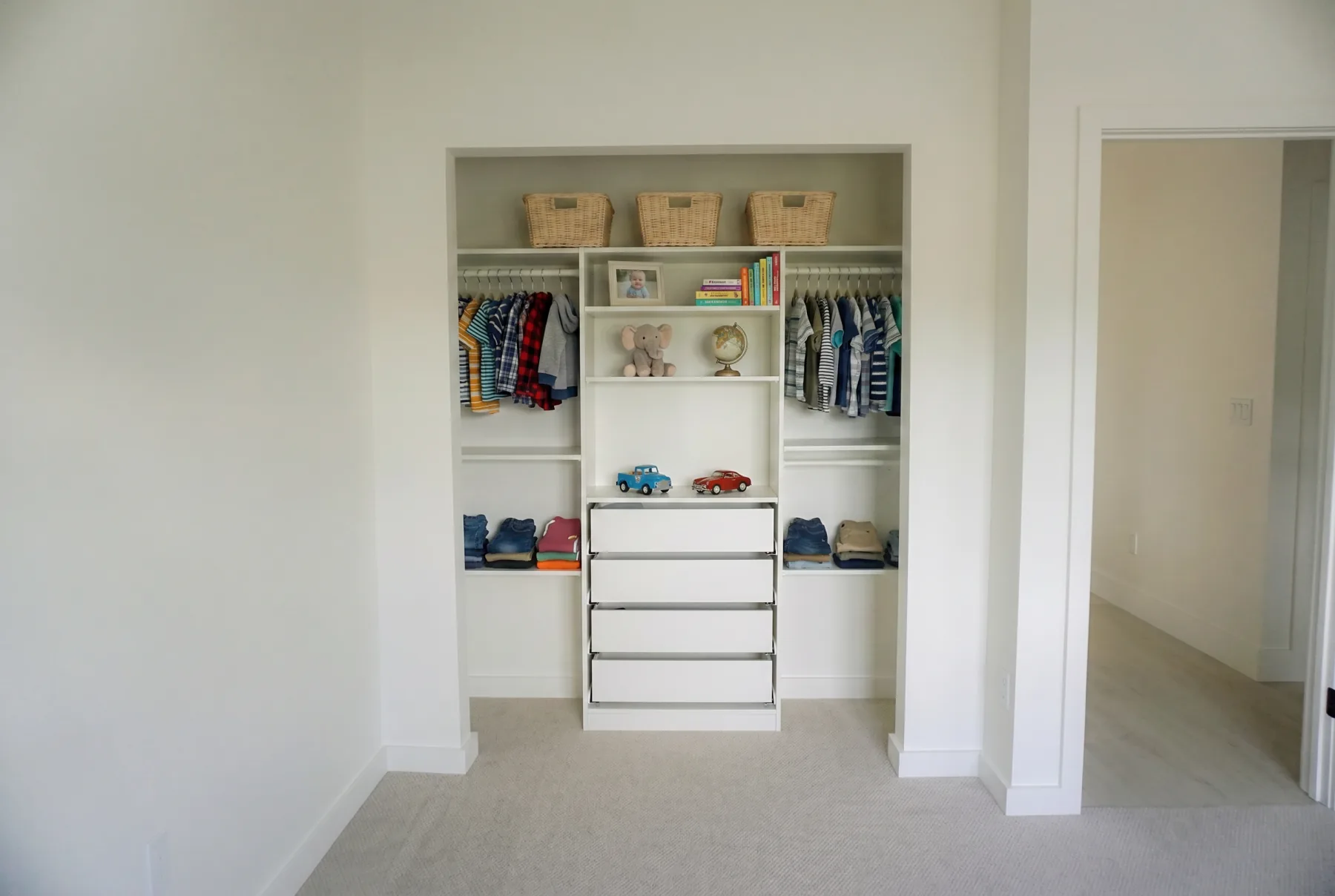 Finished kids closet with fitted shelving, drawers, baskets, and organized clothing.